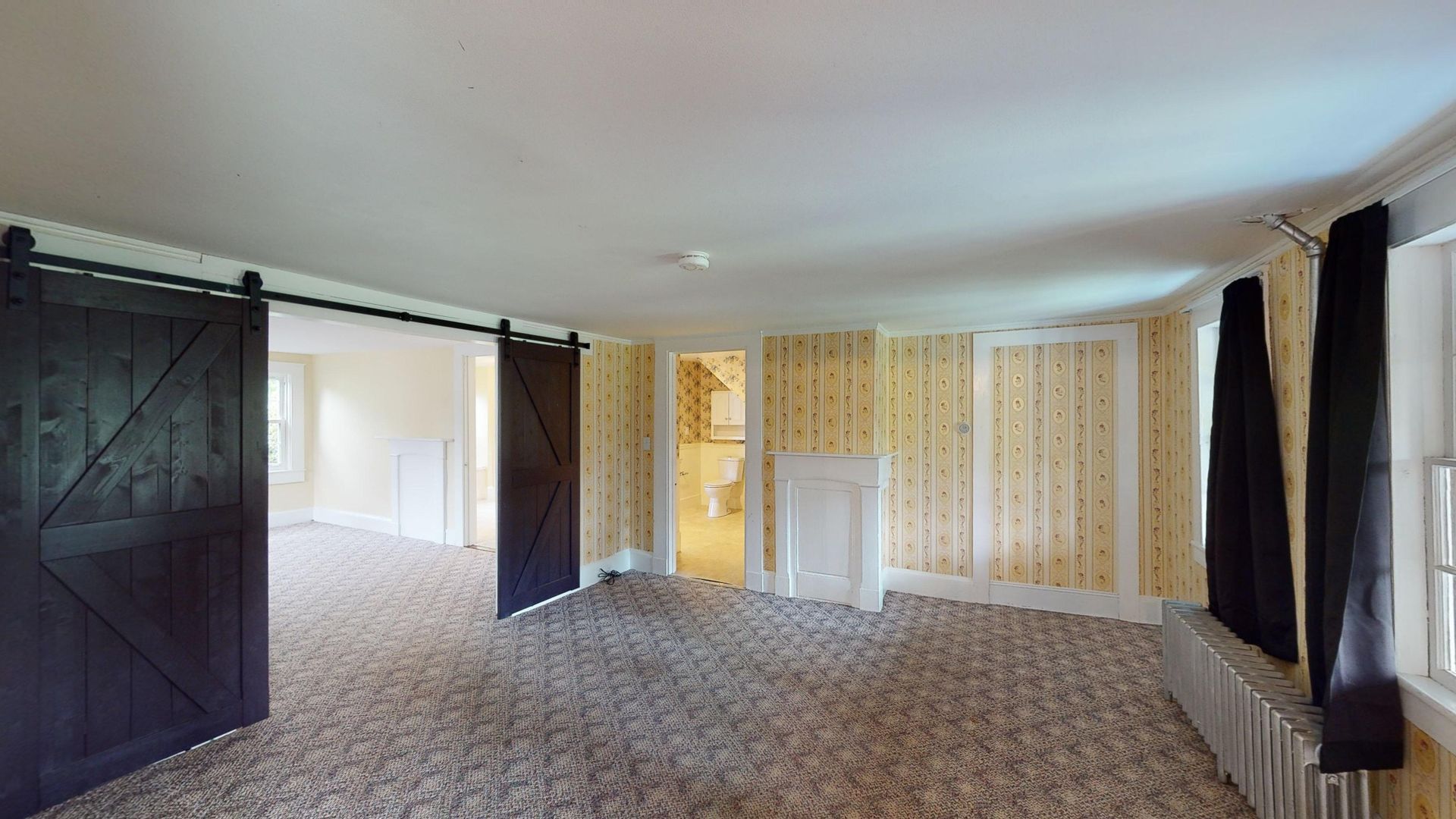 A large empty room with sliding barn doors and a fireplace.