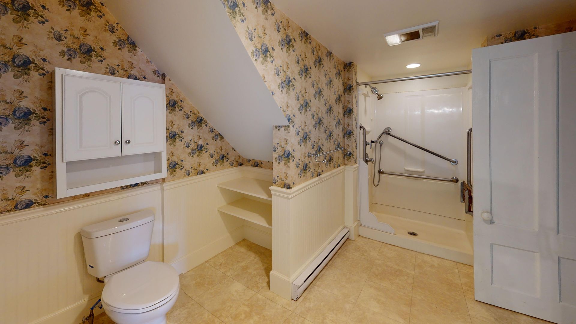 A bathroom with a toilet , shower and cabinets.