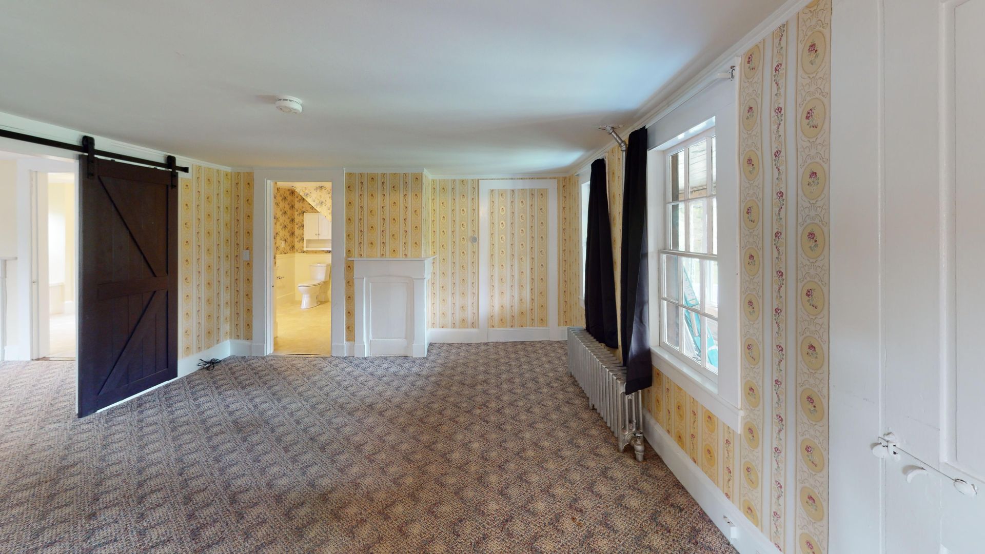 An empty room with a sliding barn door and a fireplace.
