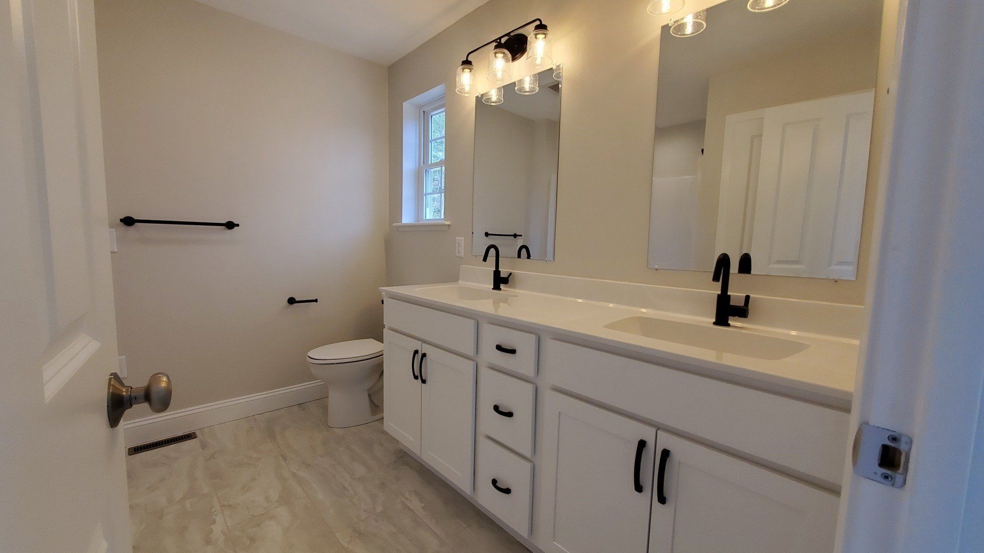 A bathroom with two sinks , a toilet , and a mirror.