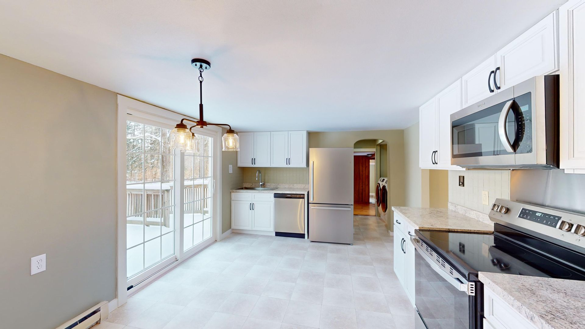 A kitchen with a stove , refrigerator , microwave and sliding glass doors.