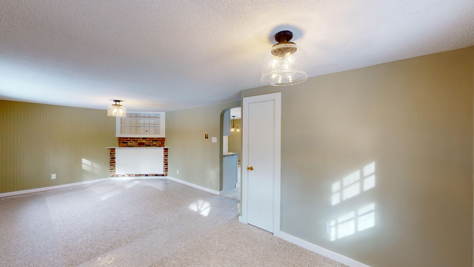 An empty living room with a fireplace and a door.