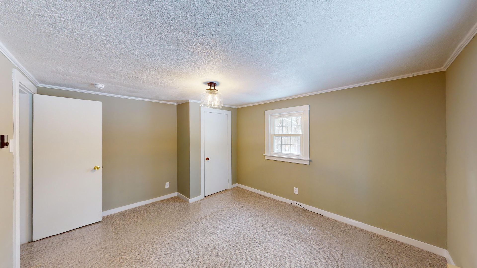 An empty bedroom with a window and a closet.