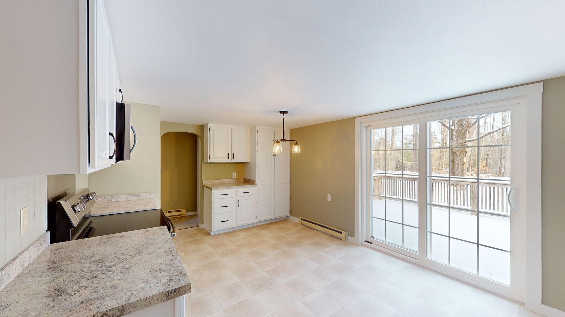 An empty kitchen with sliding glass doors leading to a patio.