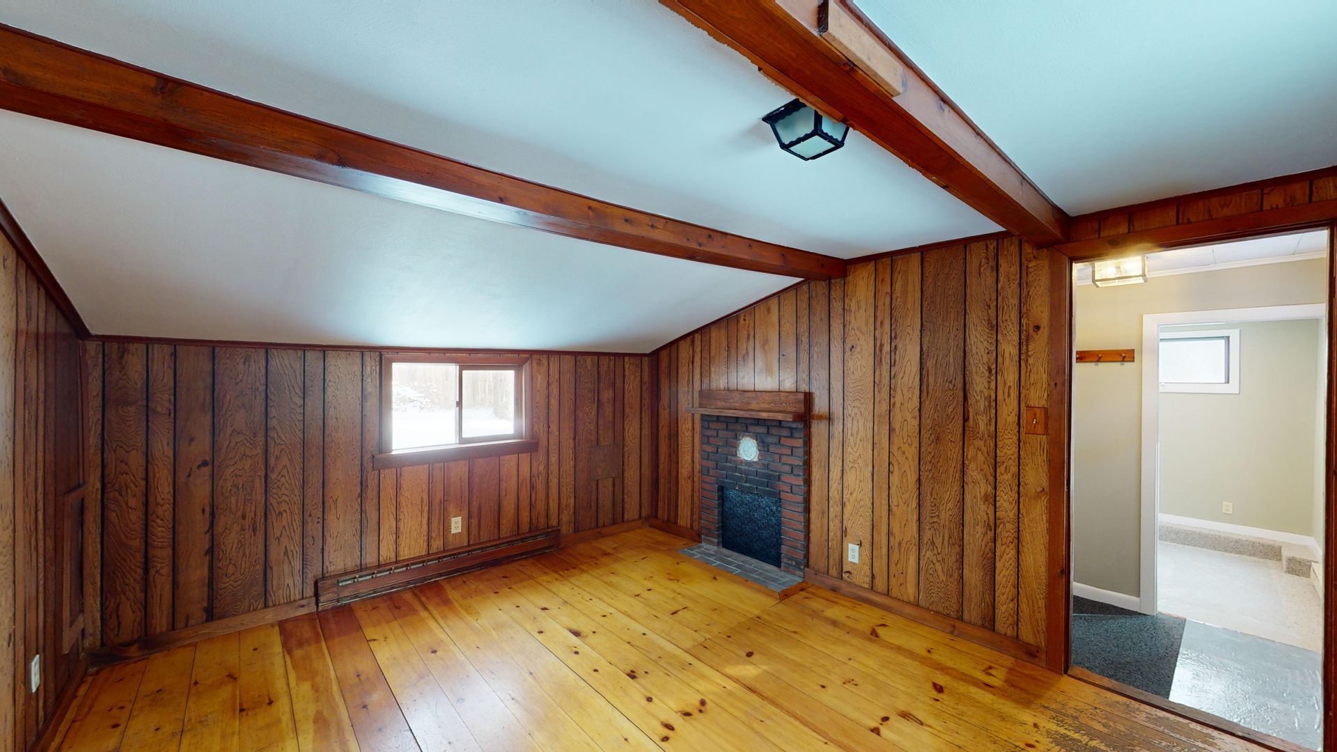 An empty room with wood paneling and a fireplace.