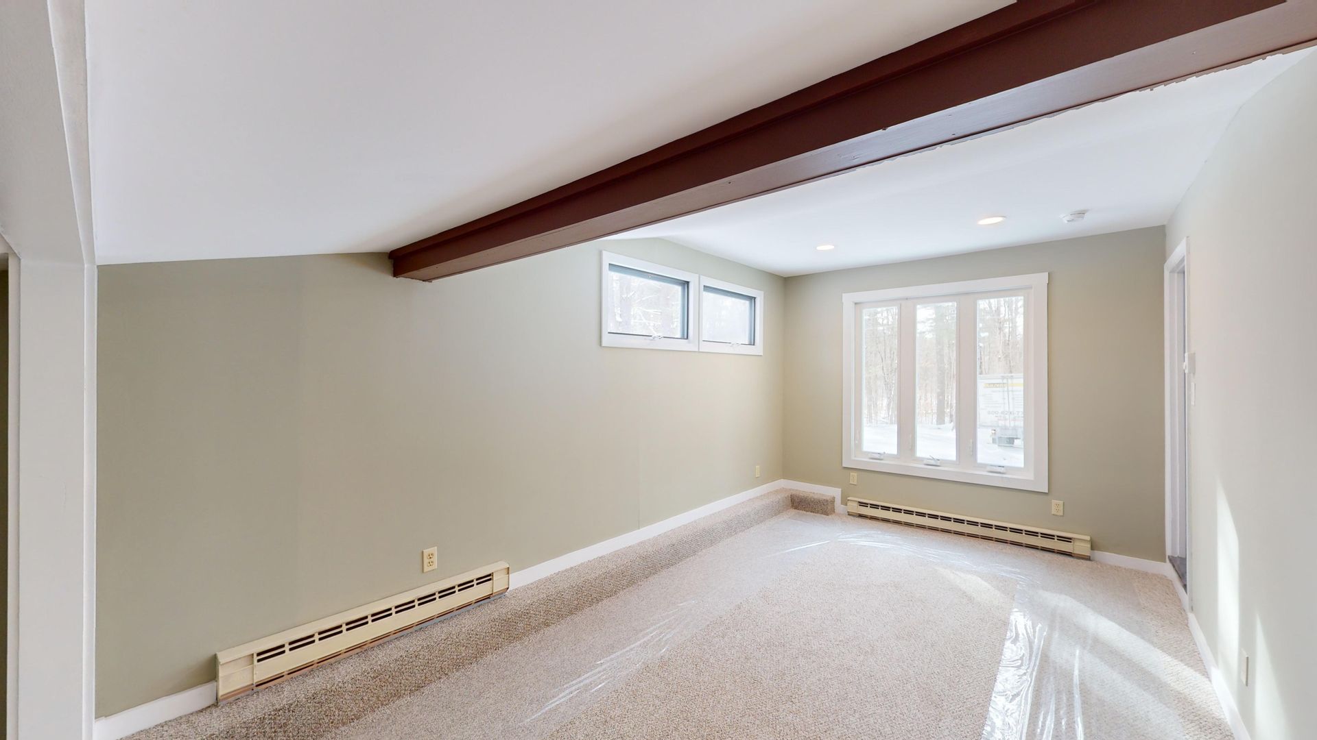 An empty living room with a lot of windows and a ceiling fan.