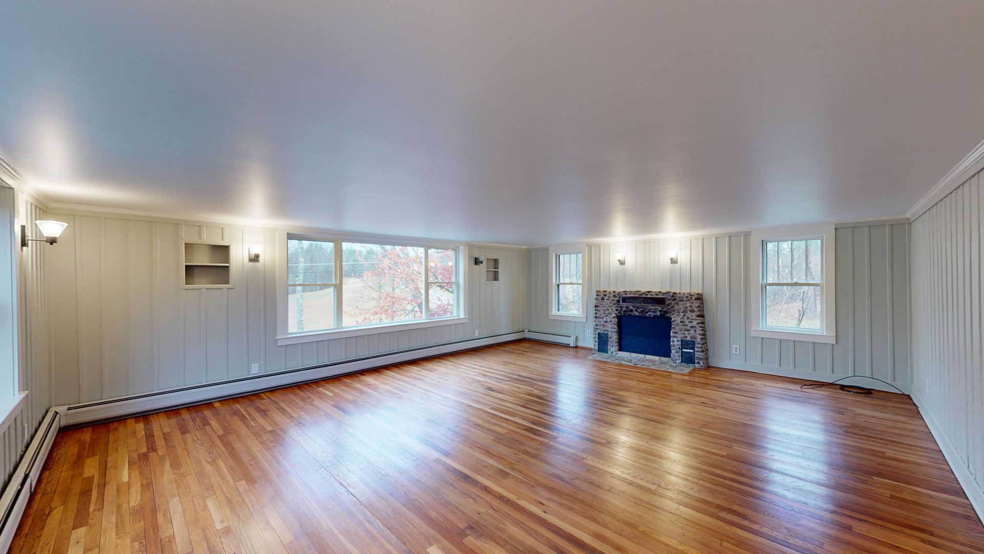 An empty living room with hardwood floors and a fireplace.