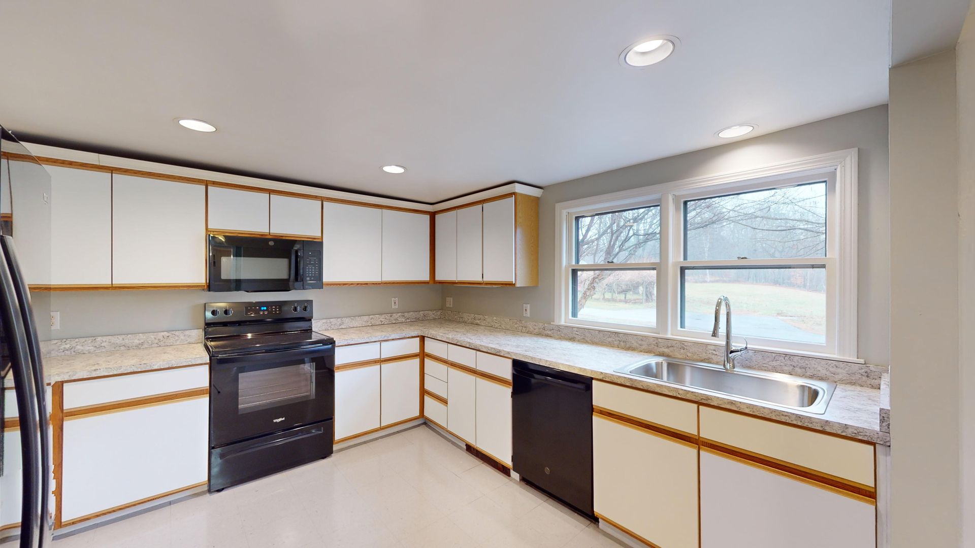 A kitchen with white cabinets , black appliances , a sink , and a stove.