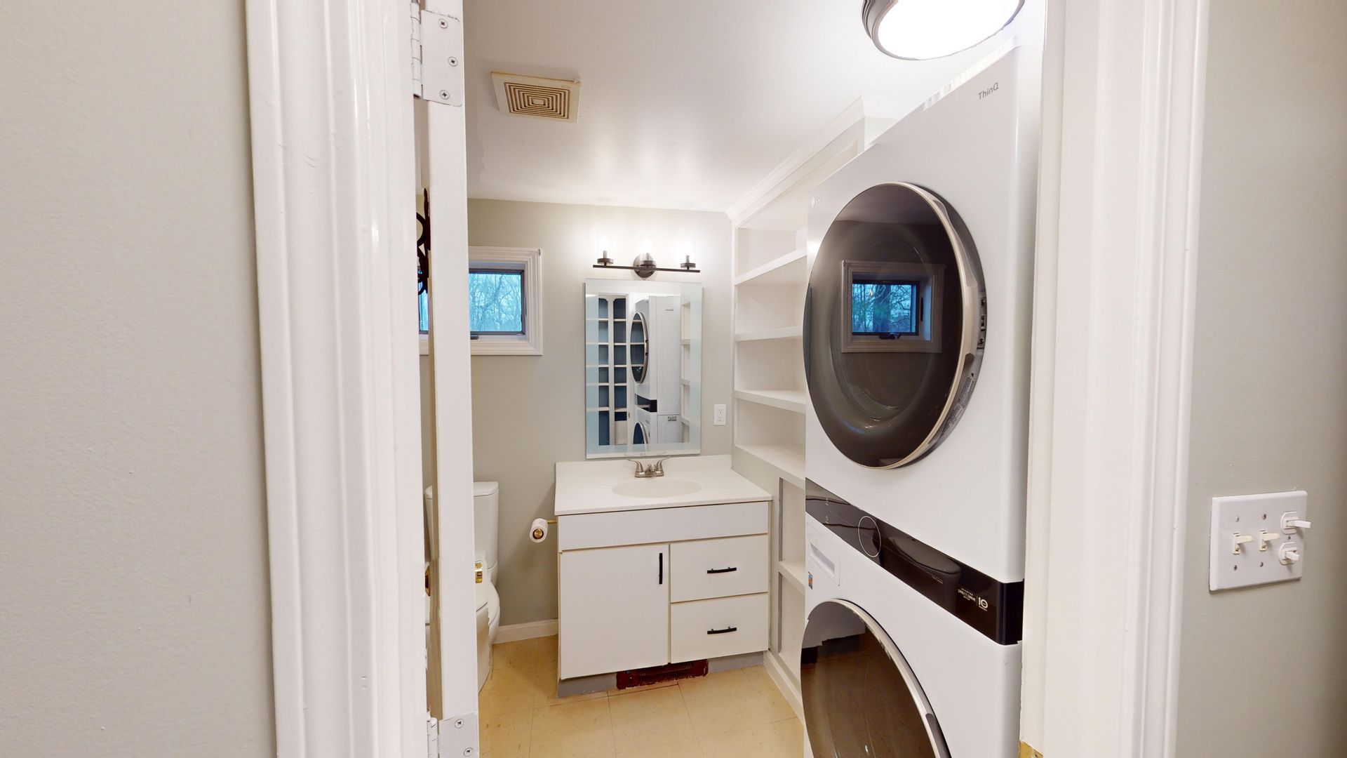 A bathroom with a washer and dryer stacked on top of each other.