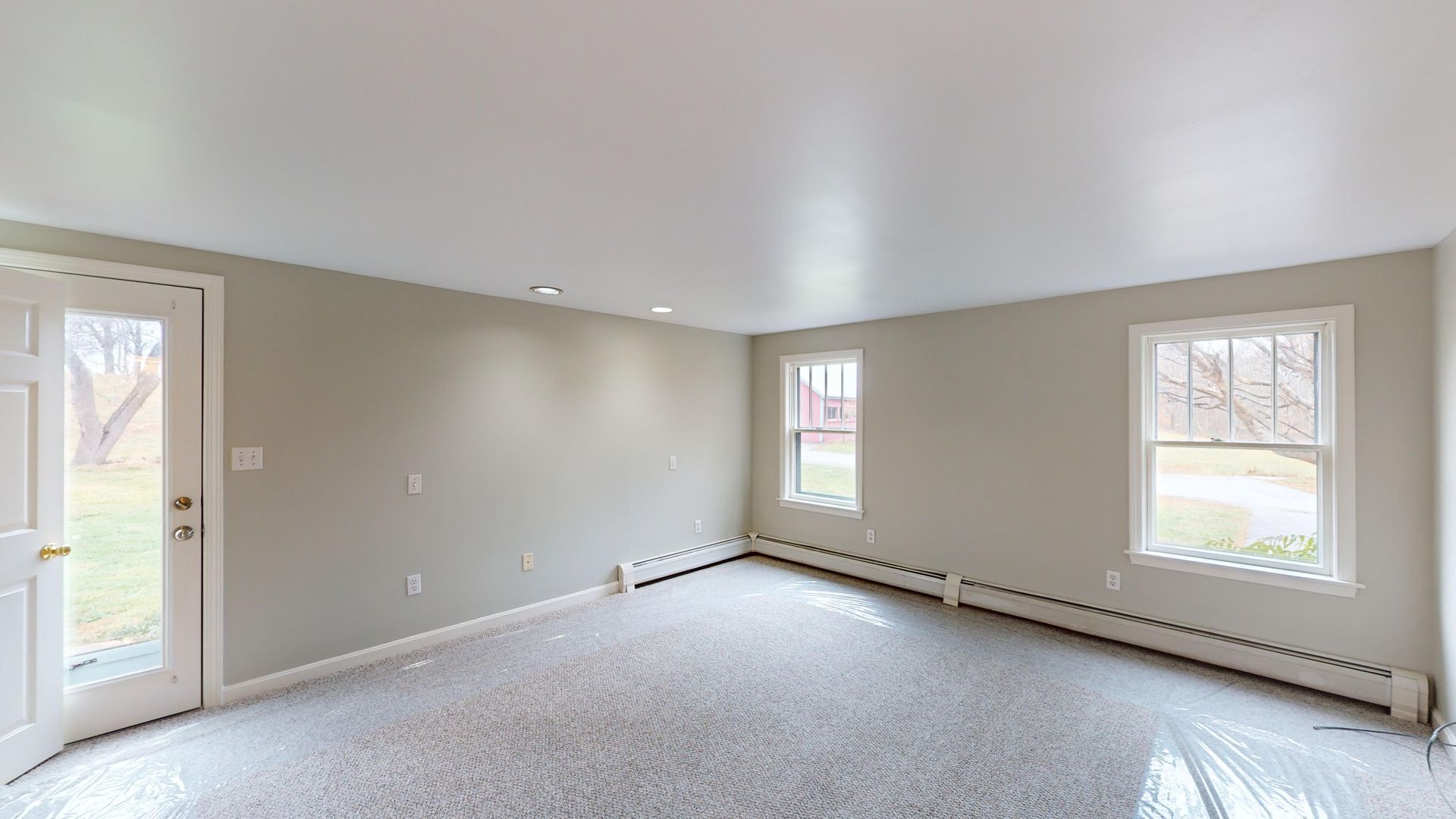 An empty living room with a carpeted floor and a sliding glass door.