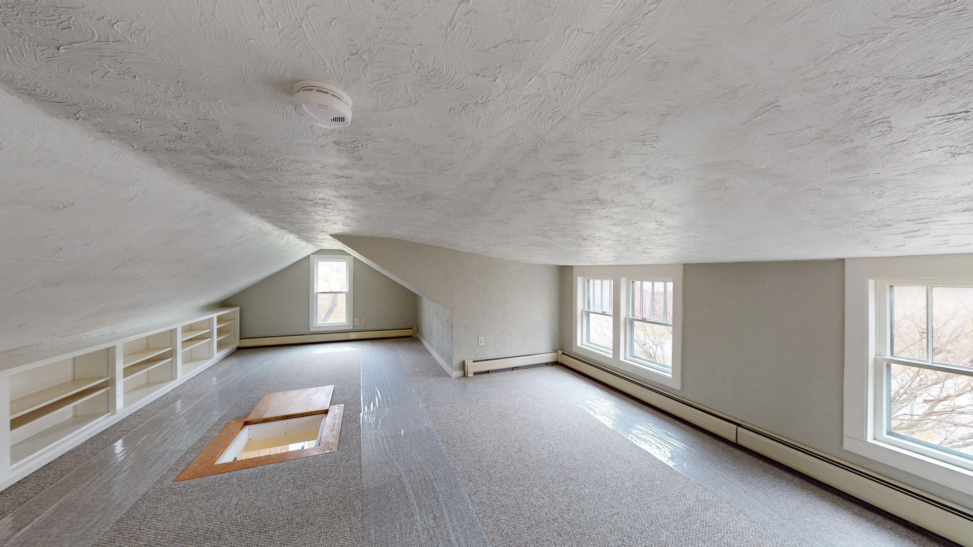 An empty attic with a vaulted ceiling and lots of windows.