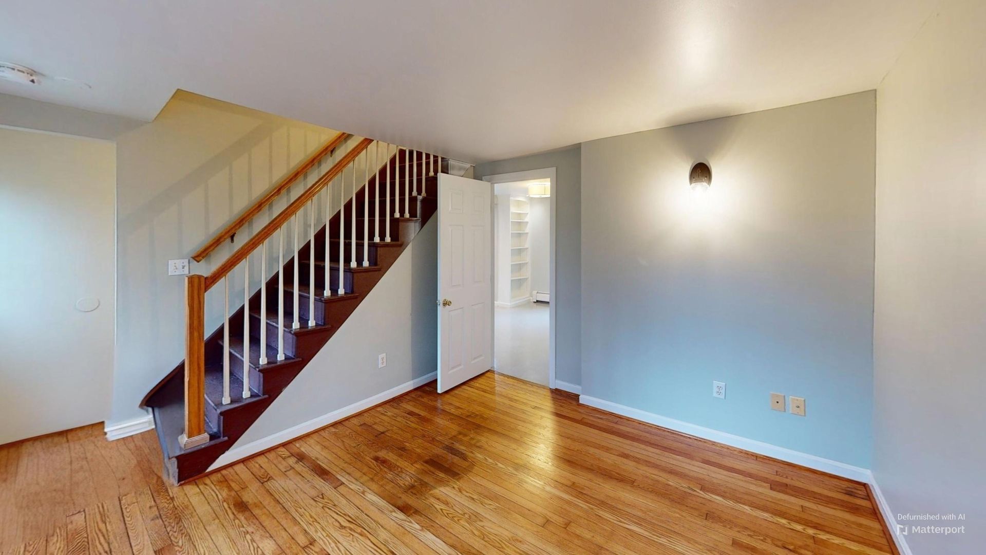 A living room with hardwood floors and stairs in a house.