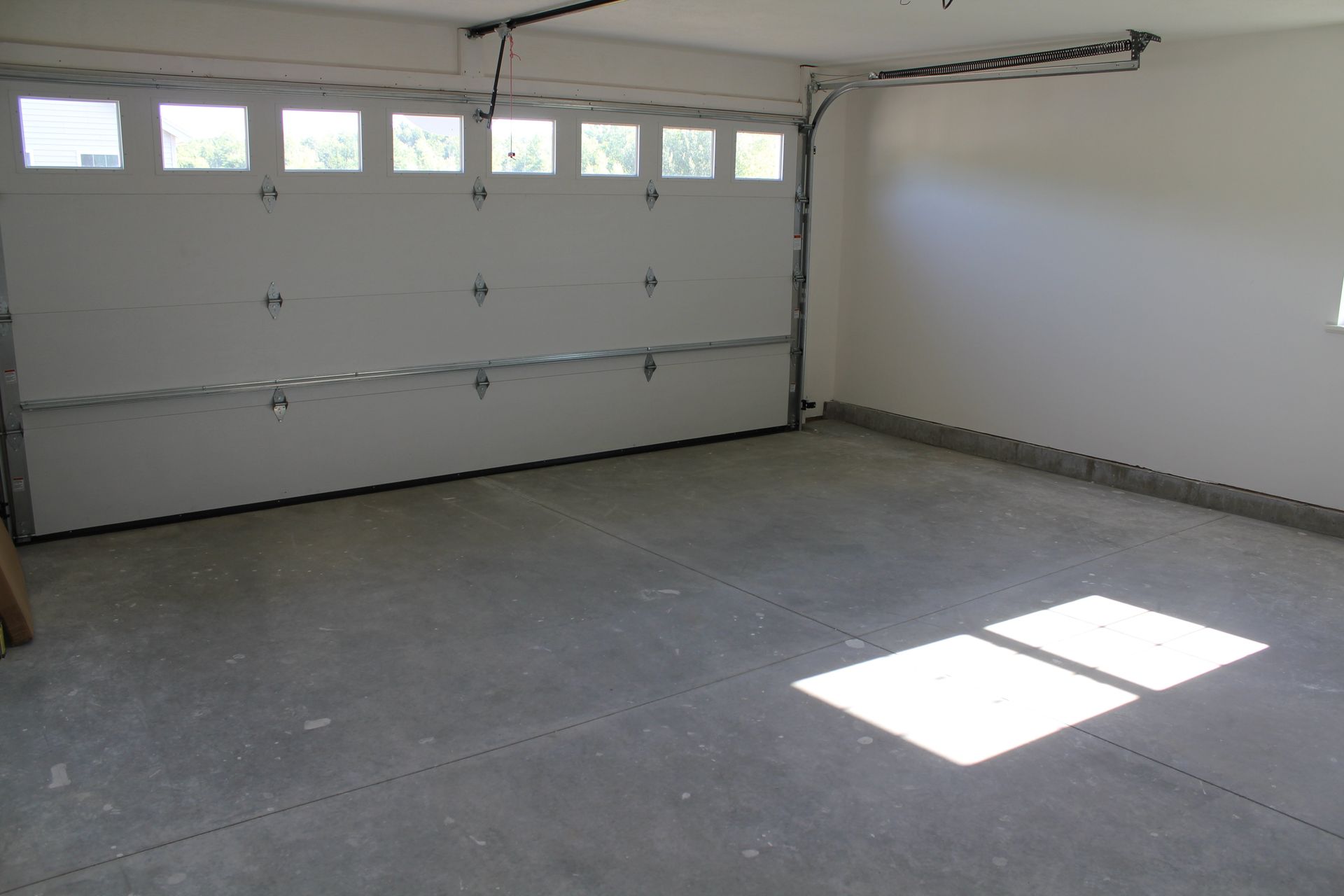 An empty garage with a garage door open and a window
