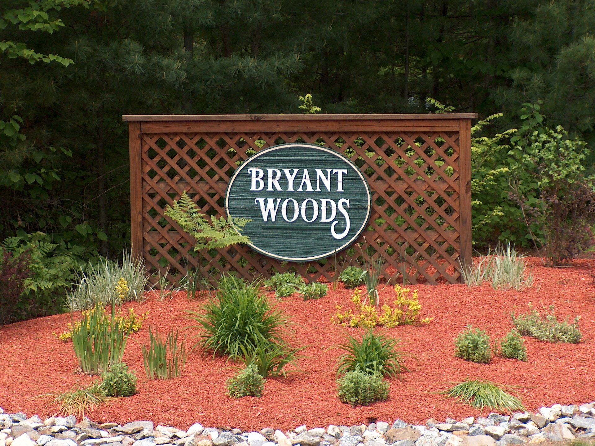 A sign for bryant woods is surrounded by rocks and plants