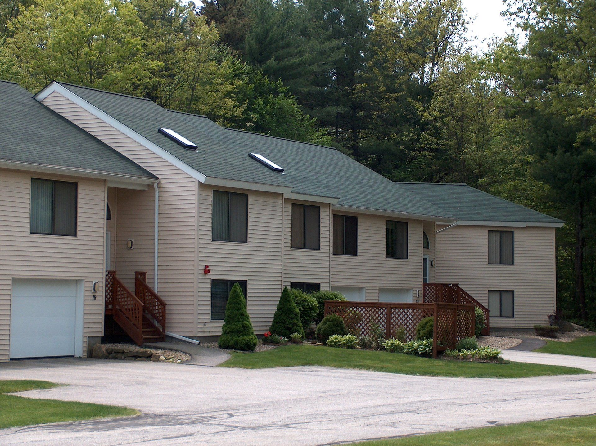 A large house with a green roof is surrounded by trees