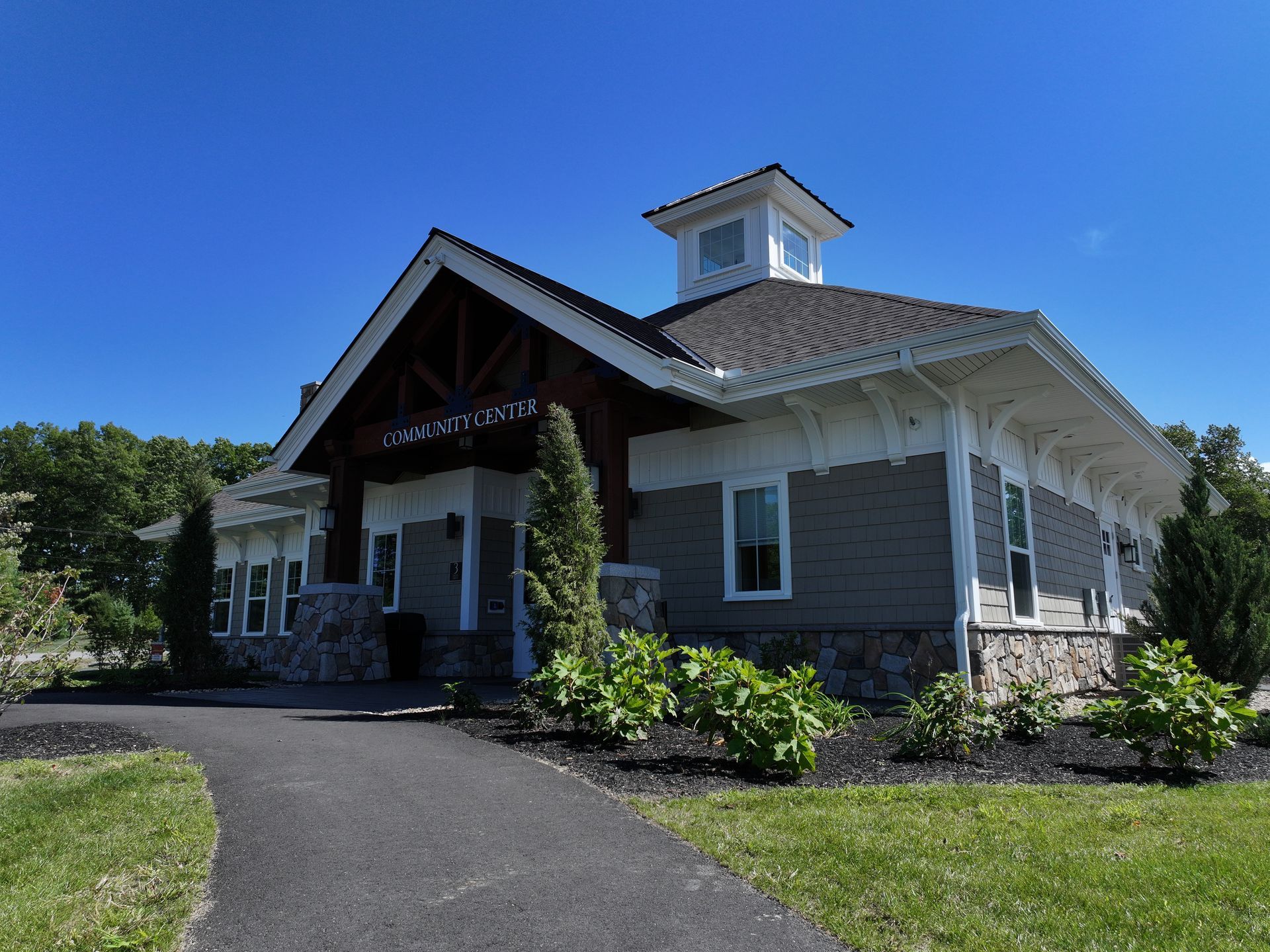A community center with a cupola on the roof is sitting on top of a lush green field.