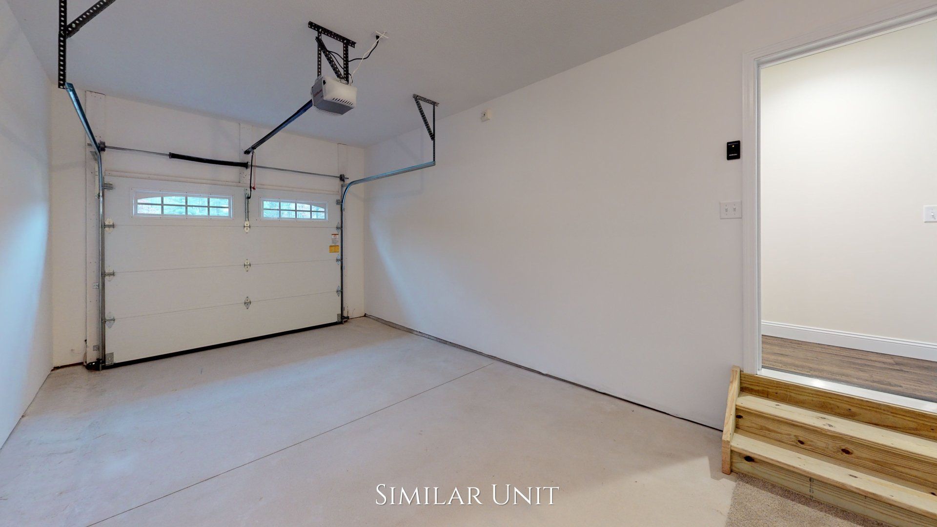 An empty garage with a garage door open and stairs leading to it.