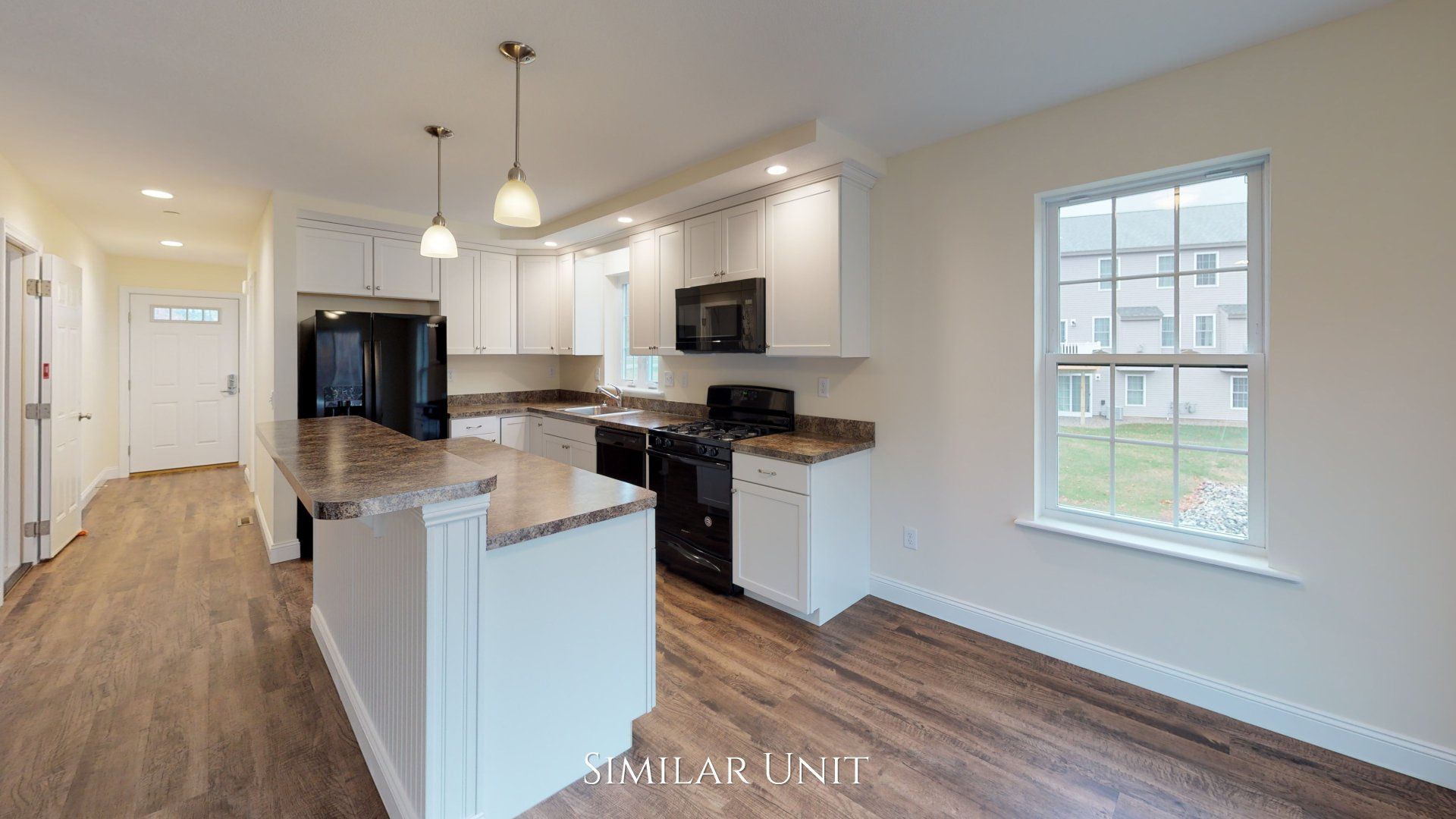 A kitchen with white cabinets , granite counter tops , black appliances and a large island.