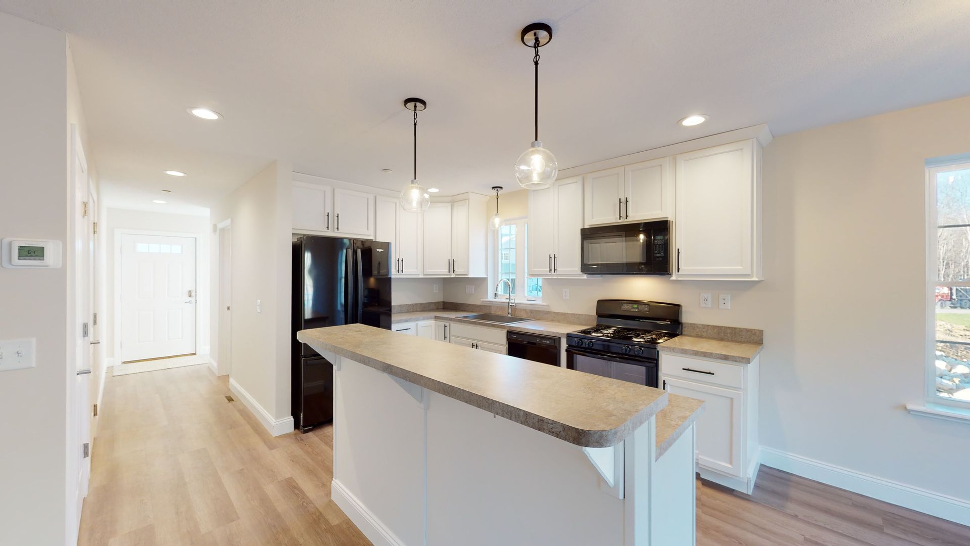 A kitchen with white cabinets , a black refrigerator , a stove and a microwave.