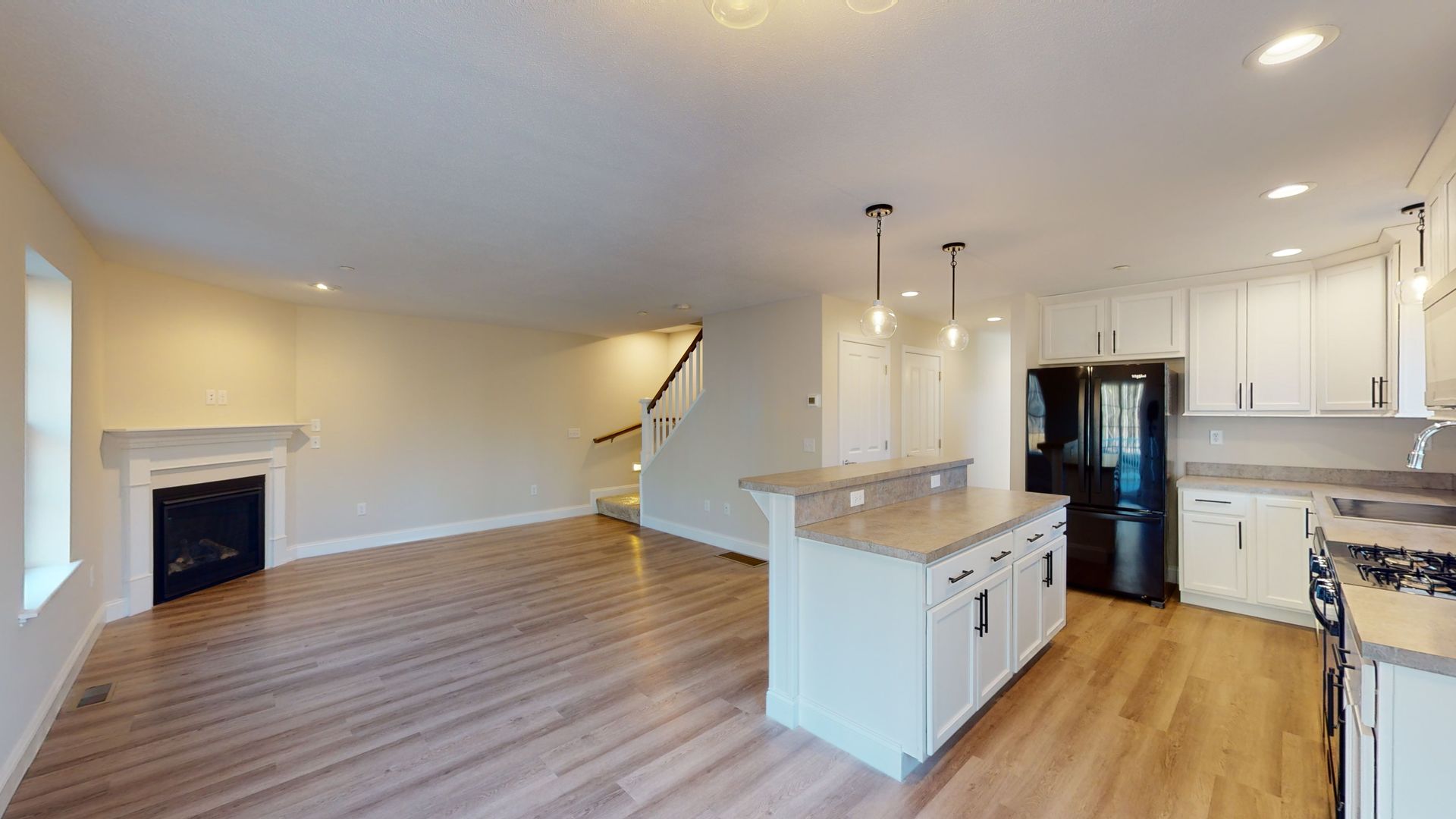 A kitchen and living room in a house with hardwood floors and white cabinets.