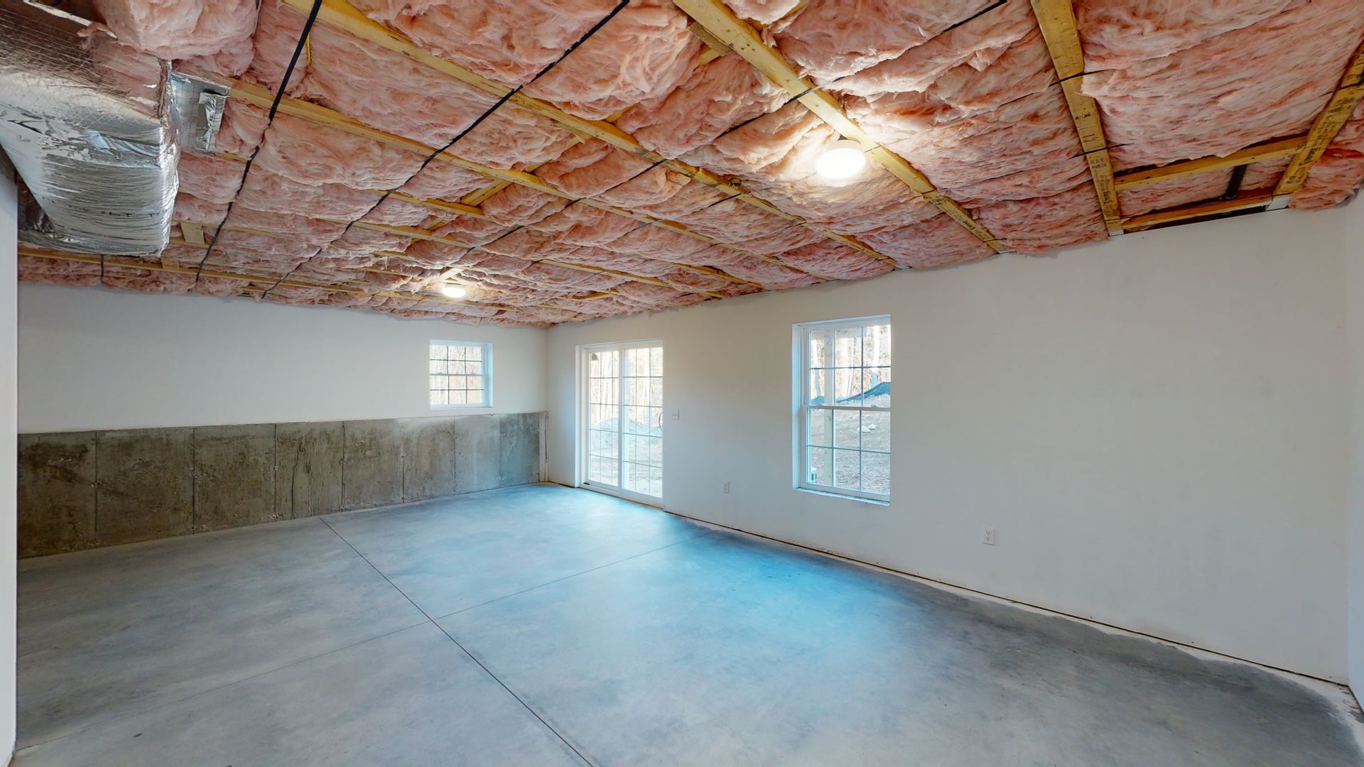 An empty room with insulation on the ceiling and a concrete floor.
