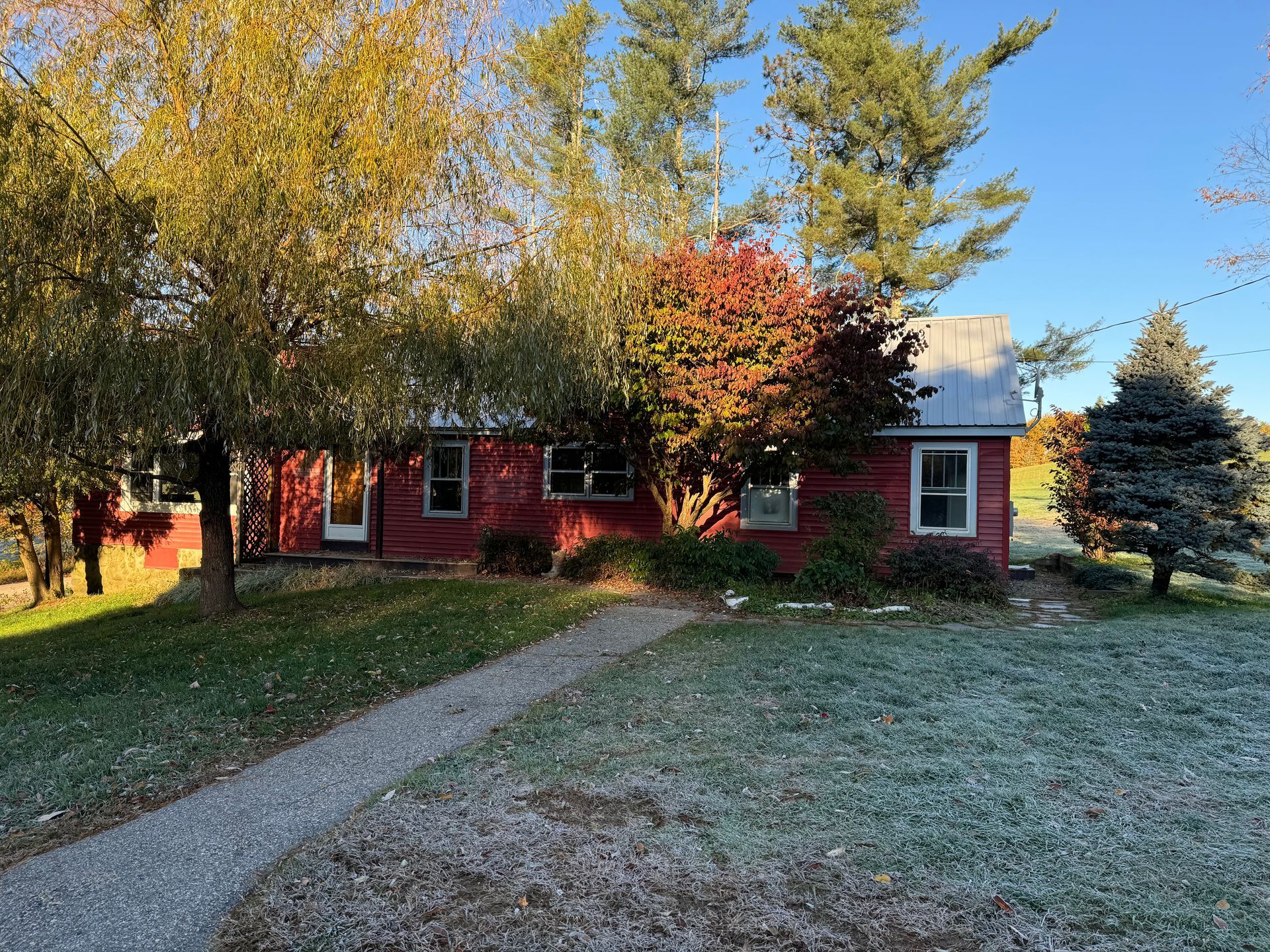 A red house with a white roof is surrounded by trees and grass.