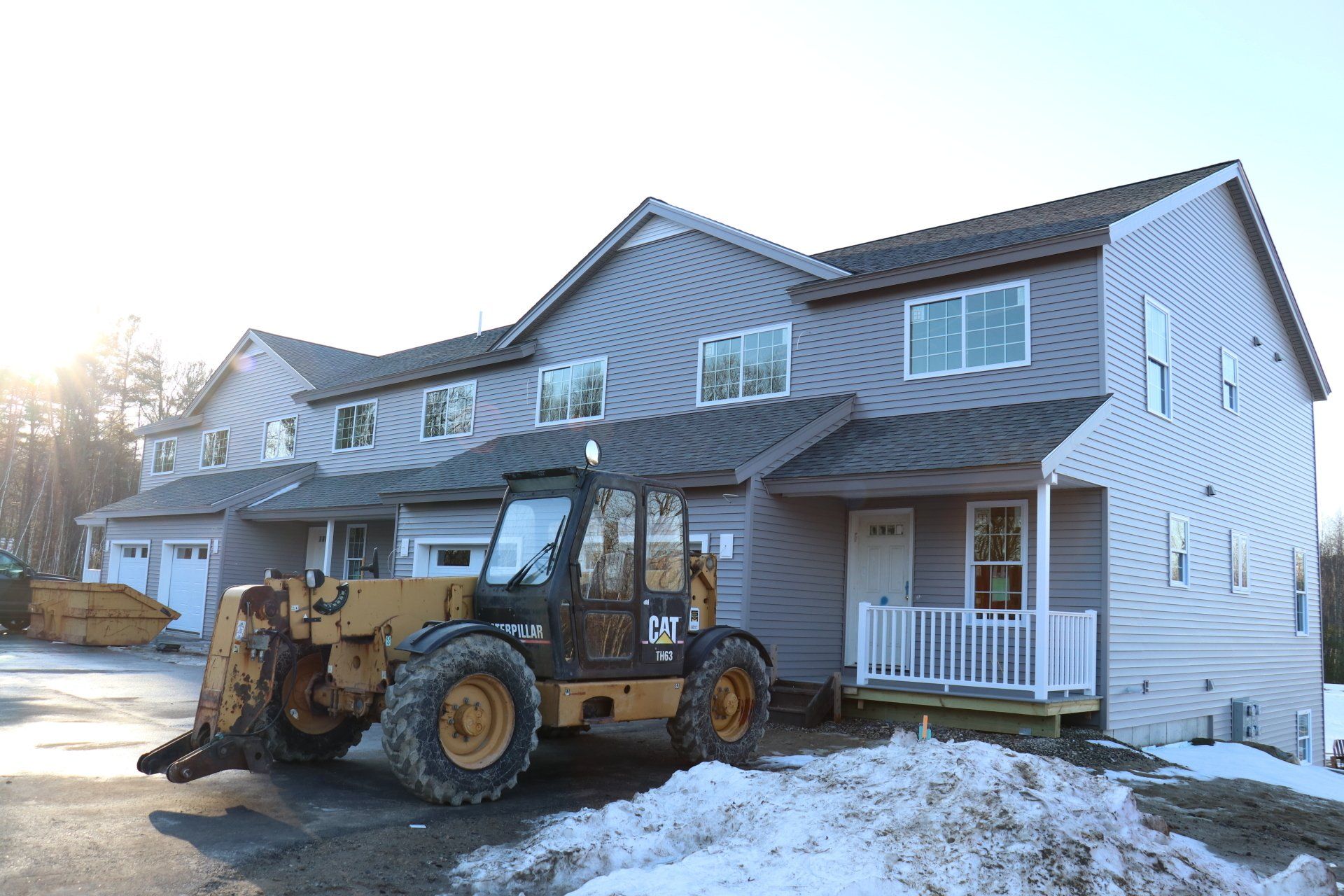 A tractor is parked in front of a house in the snow.