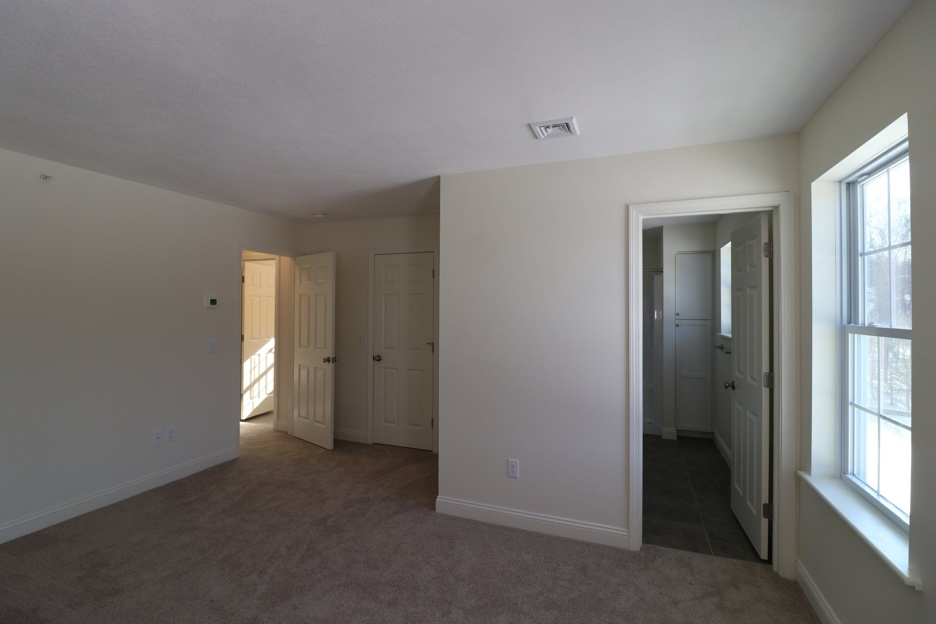 An empty bedroom with a carpeted floor and white walls