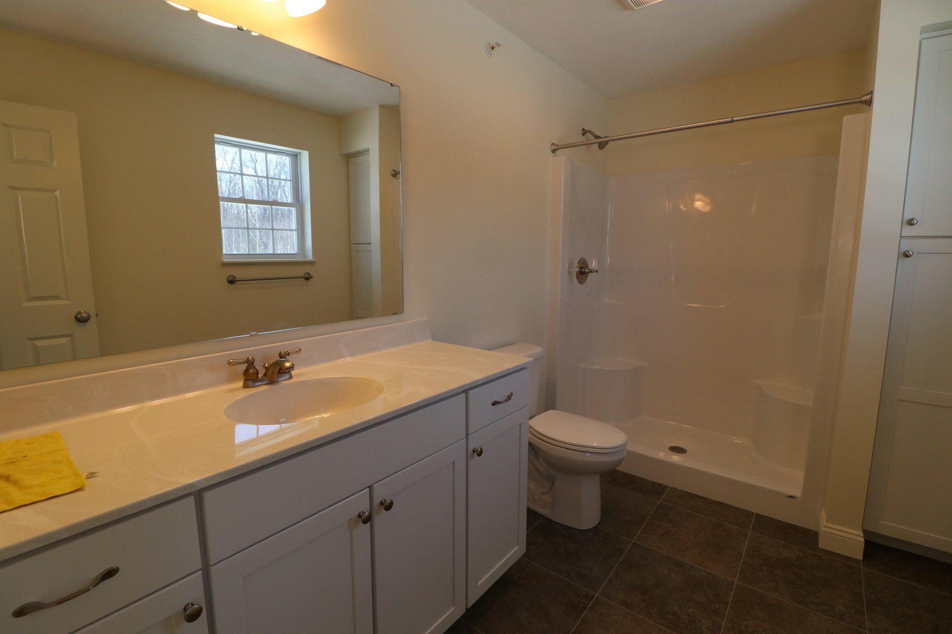 A bathroom with a sink , toilet , shower and mirror.
