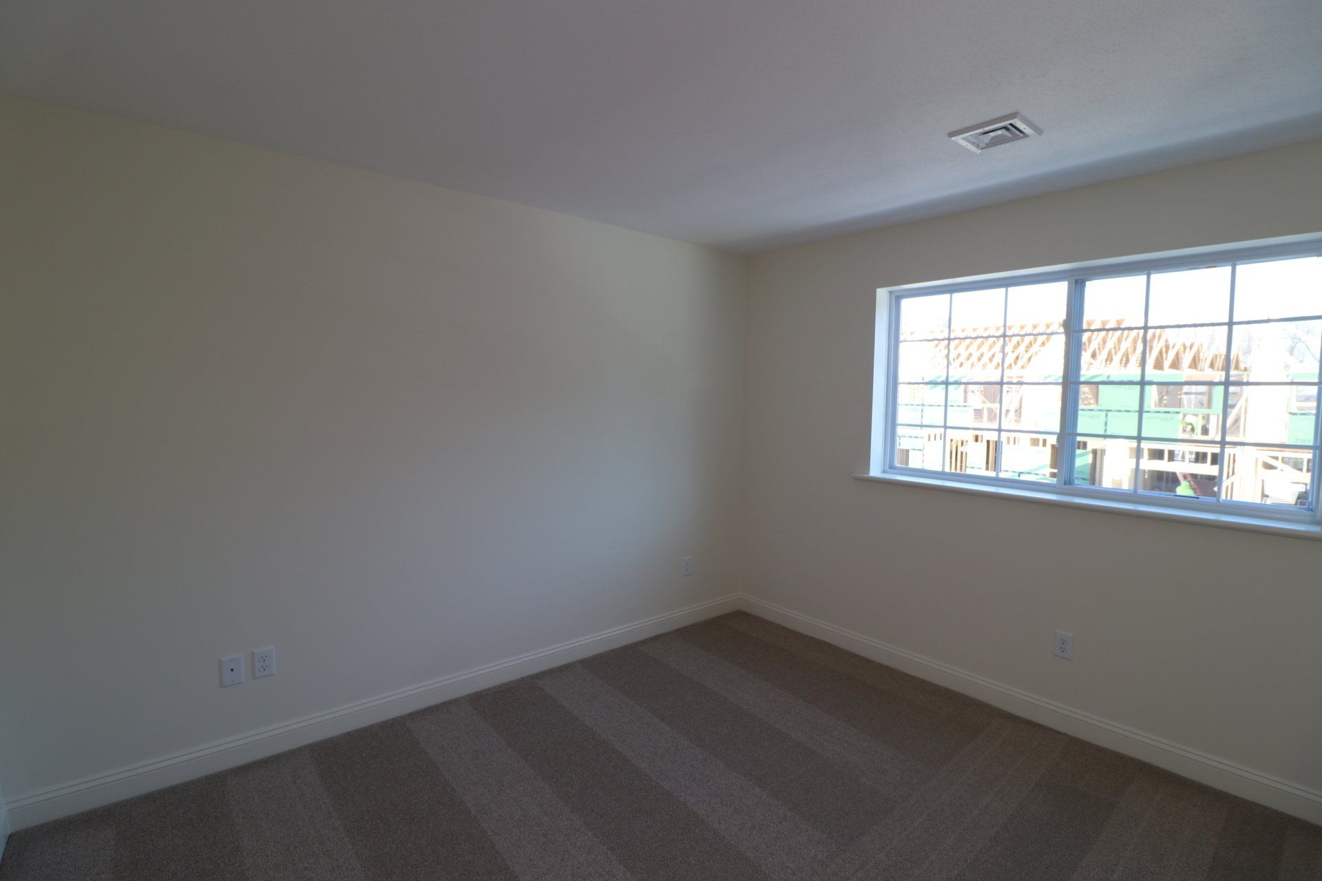 An empty room with a window and a carpeted floor