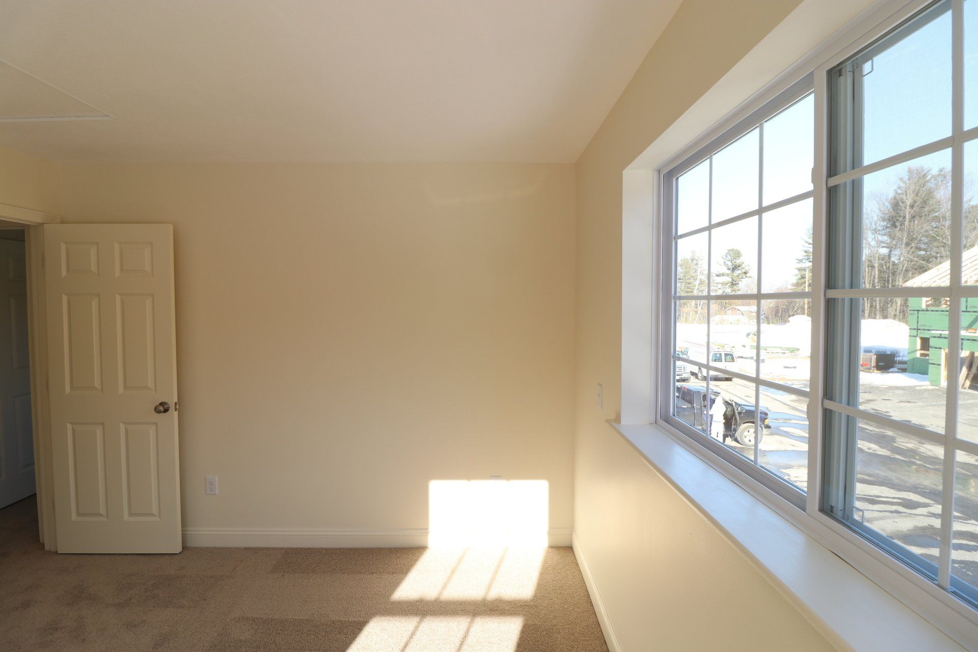 An empty room with a large window and a door.