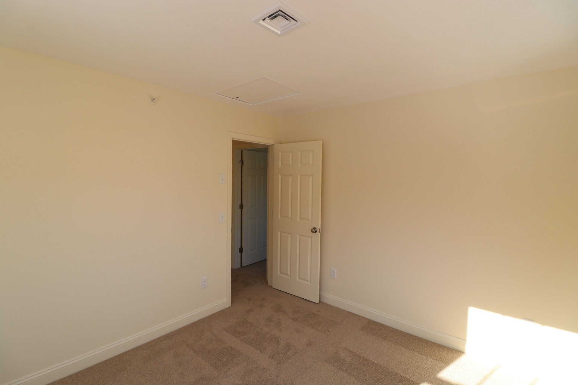 An empty bedroom with a door and a window.