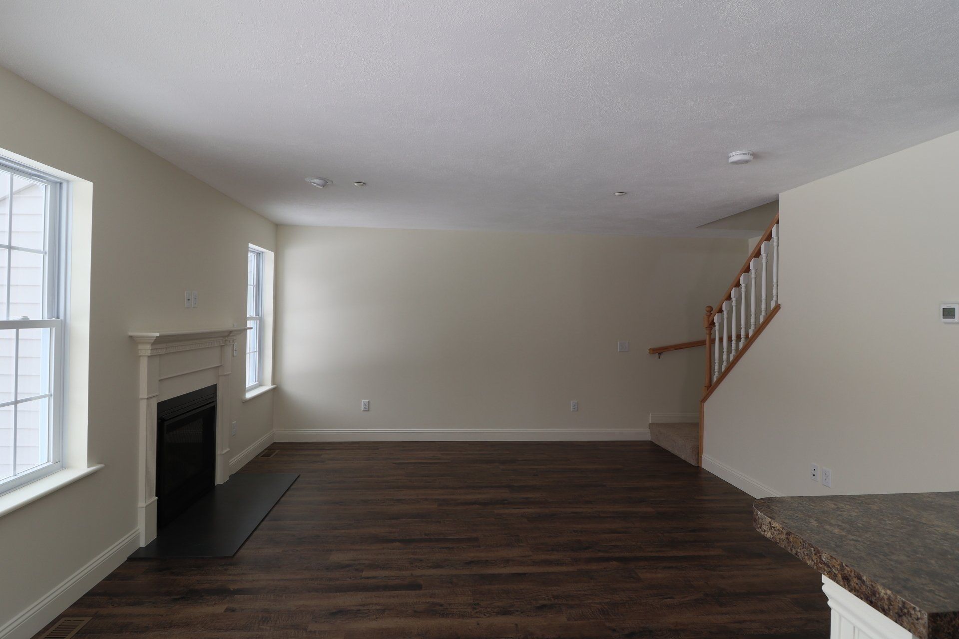 An empty living room with a fireplace and stairs.