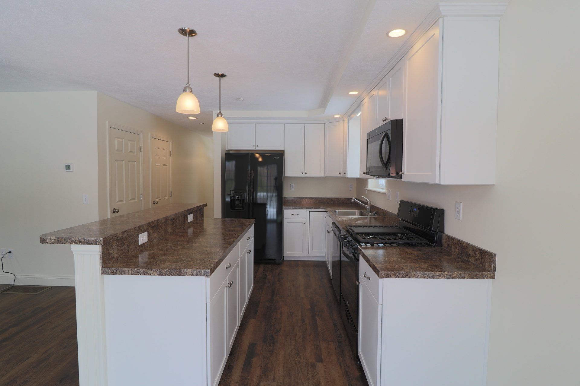 An empty kitchen with white cabinets and granite counter tops.