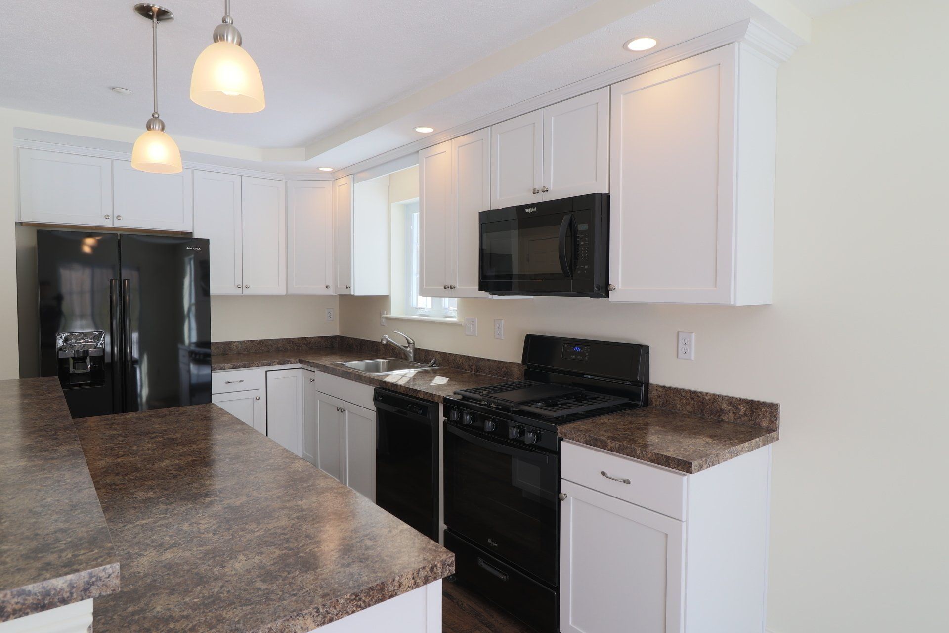 A kitchen with white cabinets , black appliances and granite counter tops.