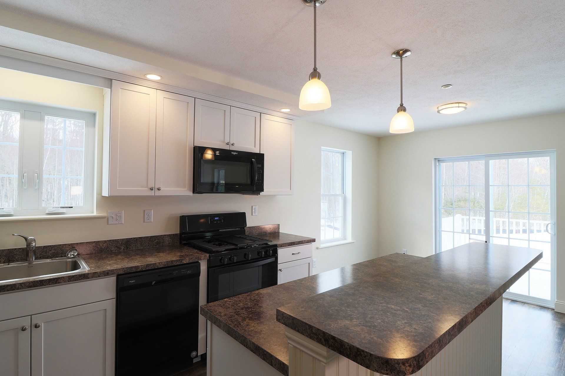 An empty kitchen with white cabinets and granite counter tops