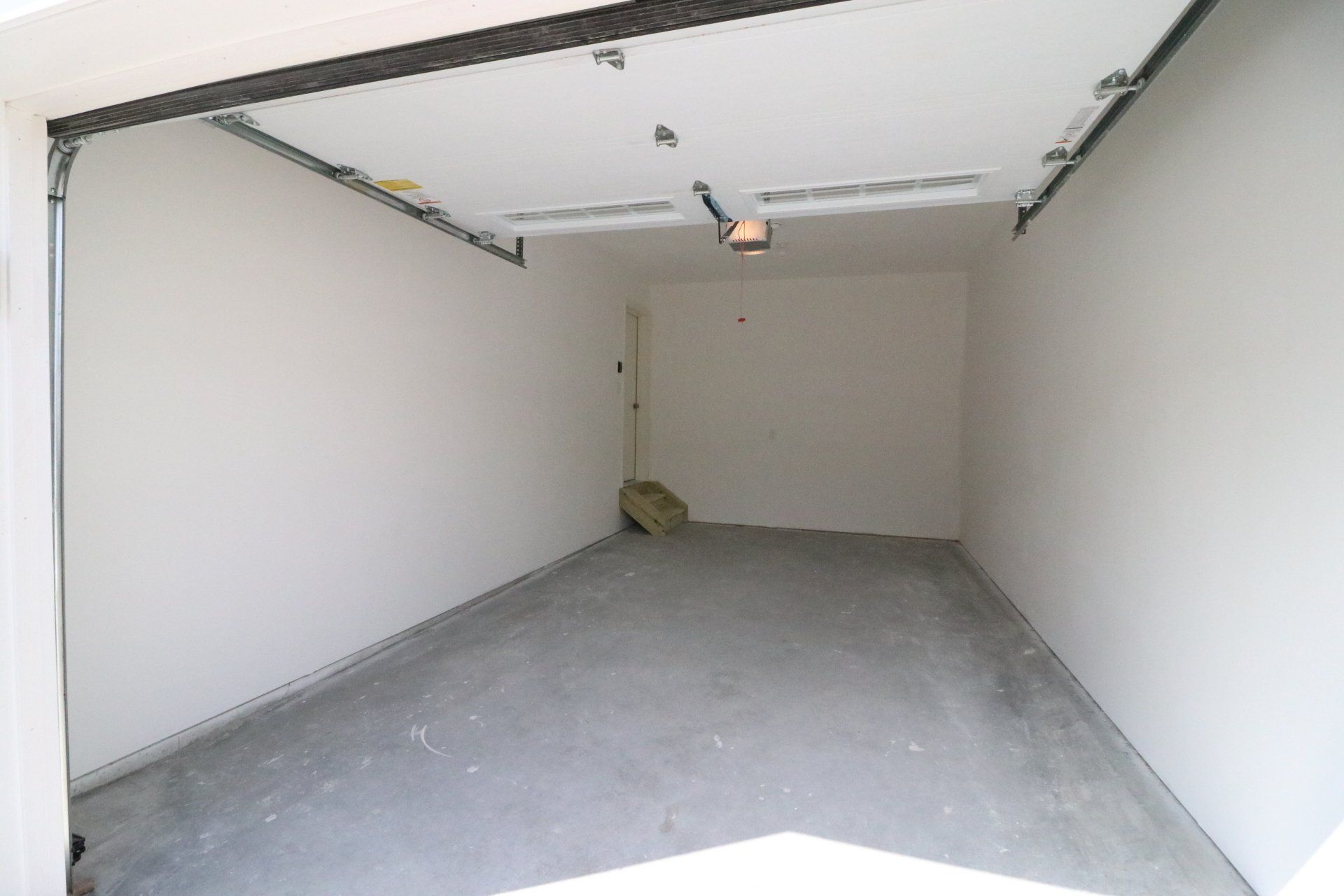 An empty garage with a garage door open and a concrete floor.