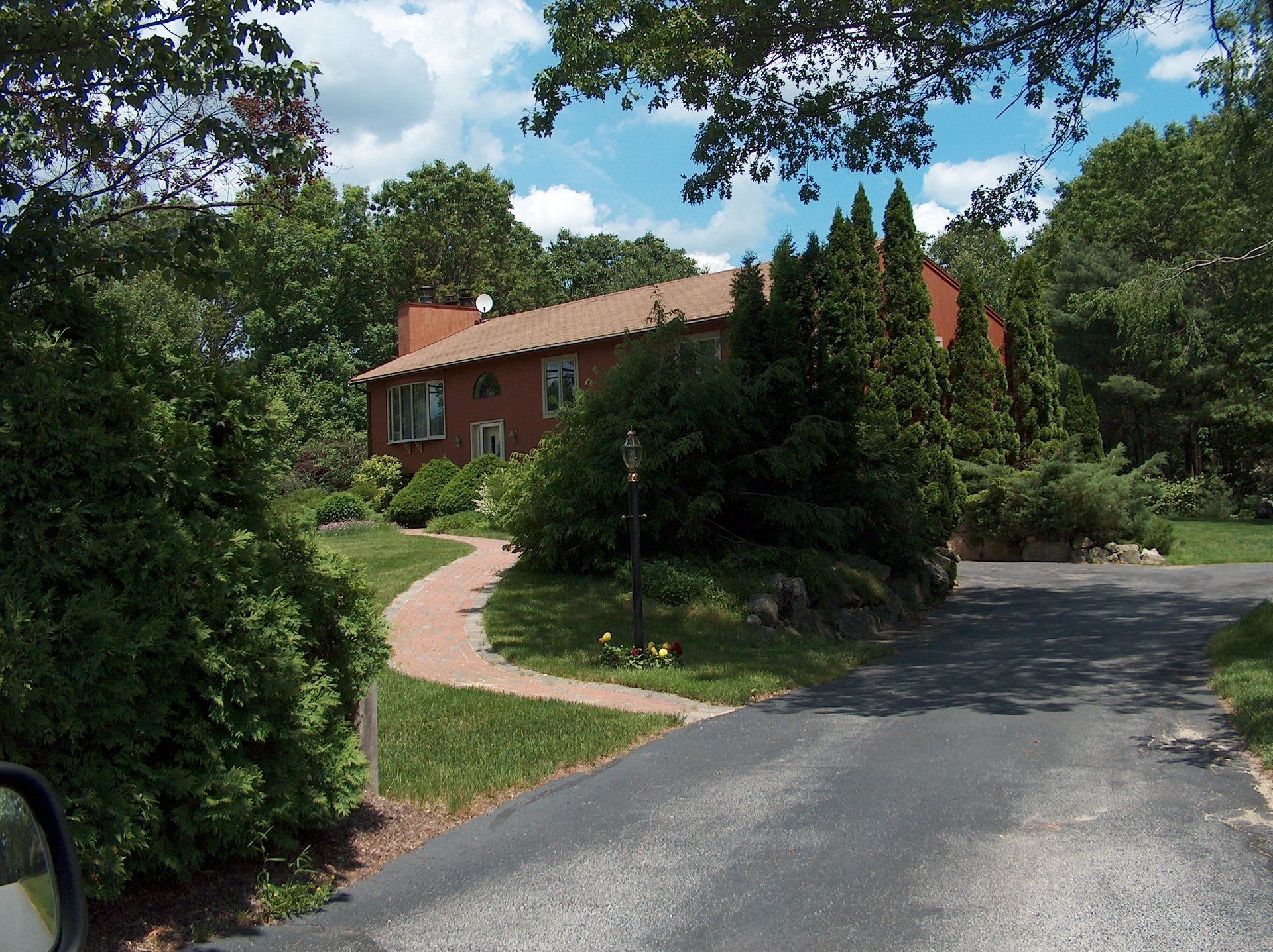 A house is surrounded by trees and bushes on a sunny day