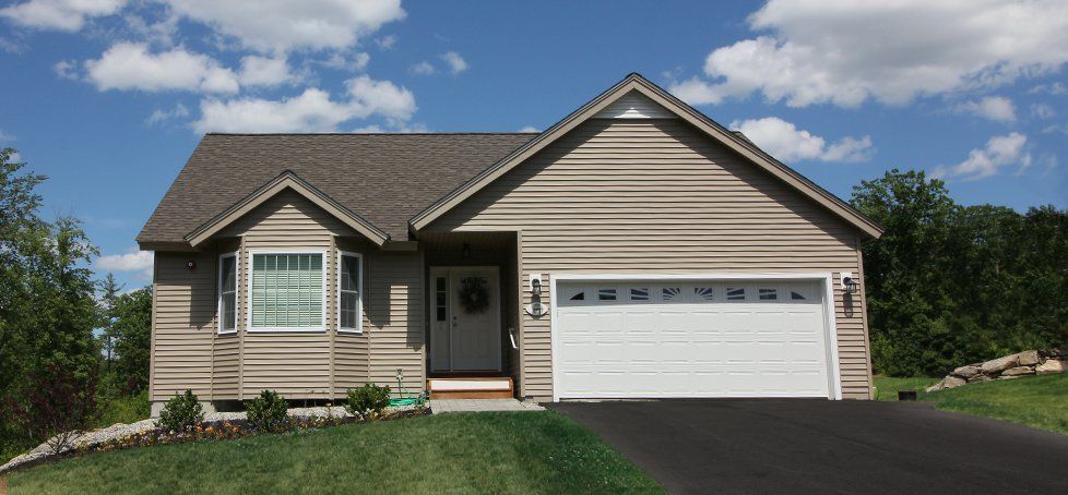 A house with a white garage door and a blue sky in the background