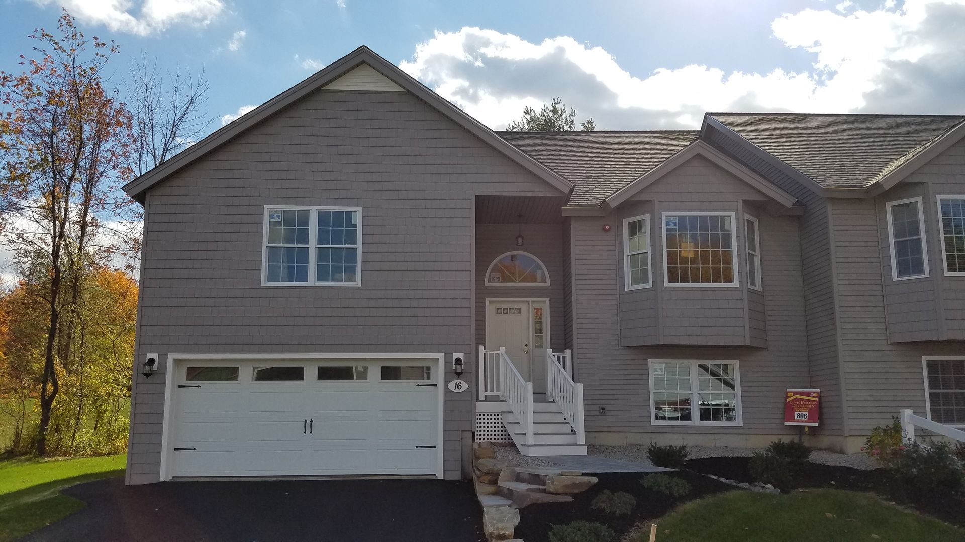 A large house with a white garage door and a mailbox in front of it.
