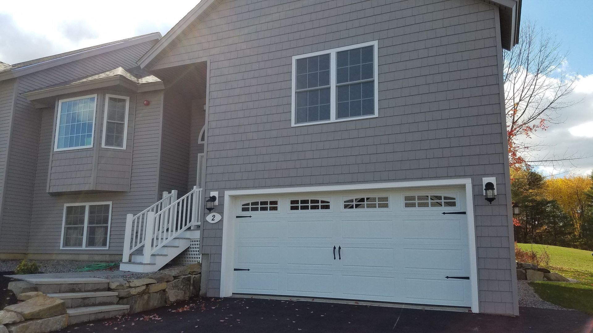 A large house with a white garage door and stairs