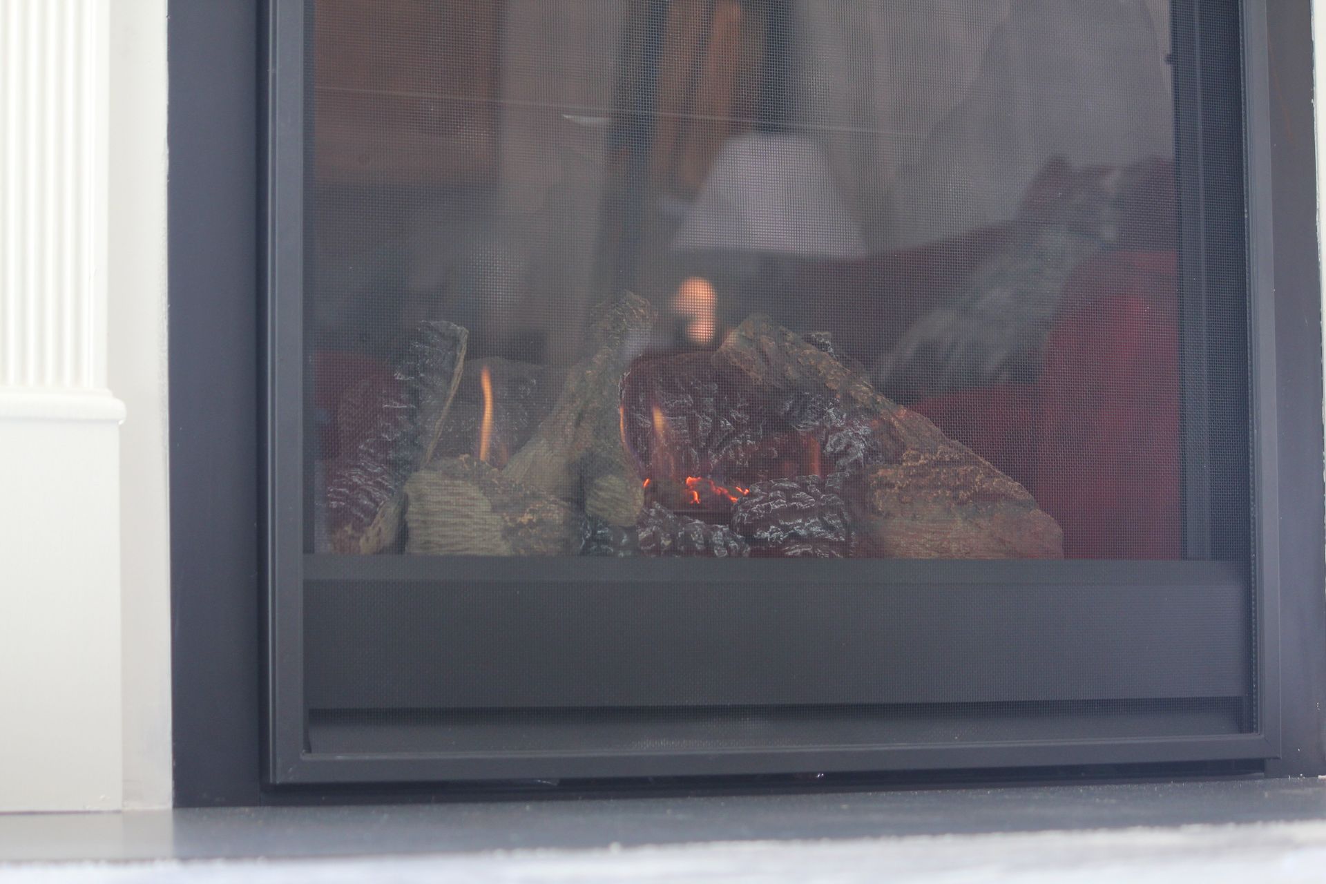 A close up of a fireplace with a reflection of a person in it.