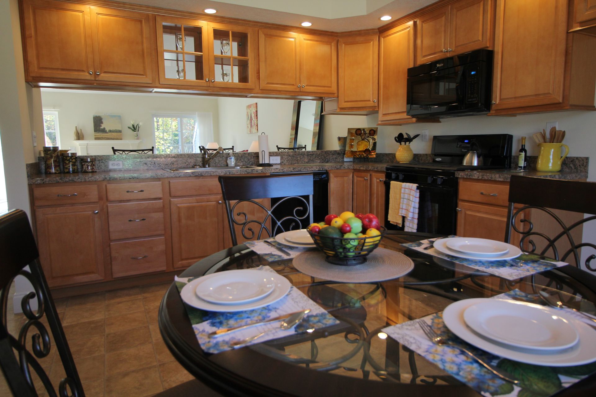 A kitchen with a dining table and chairs and a bowl of fruit on the table.