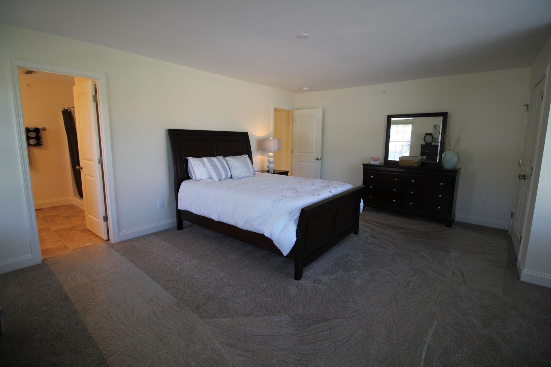 A bedroom with a bed , dresser and mirror.