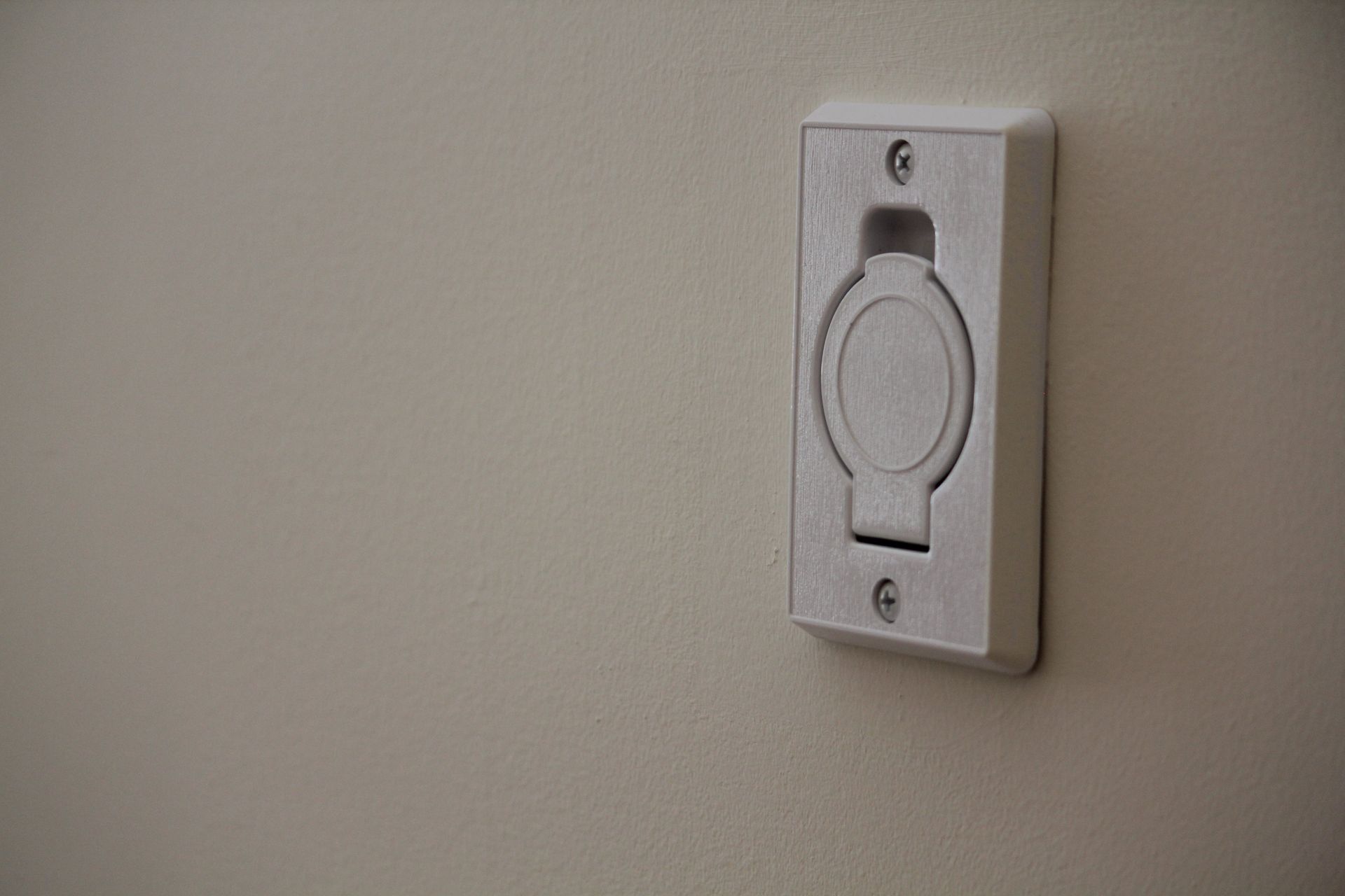 A white electrical outlet is hanging on a white wall.