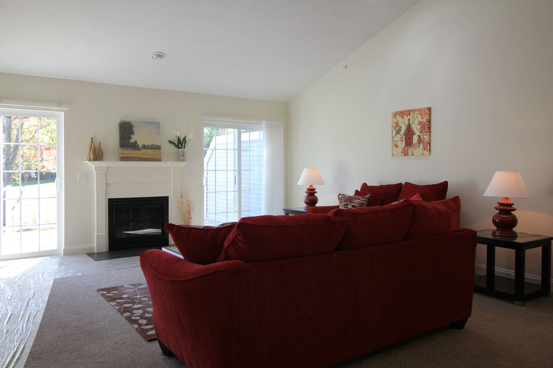 A living room with a red couch and a fireplace