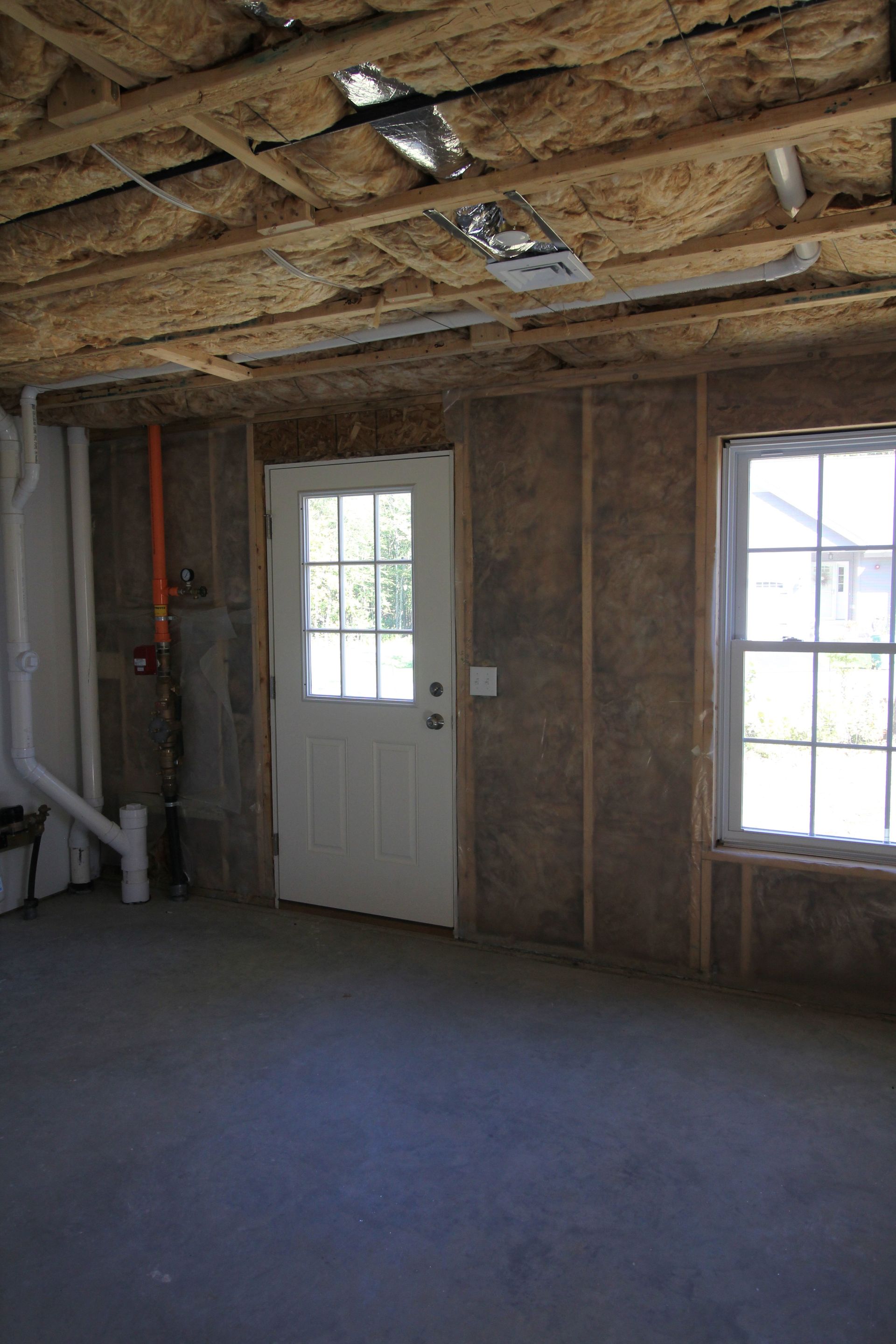 An empty room with a white door and two windows