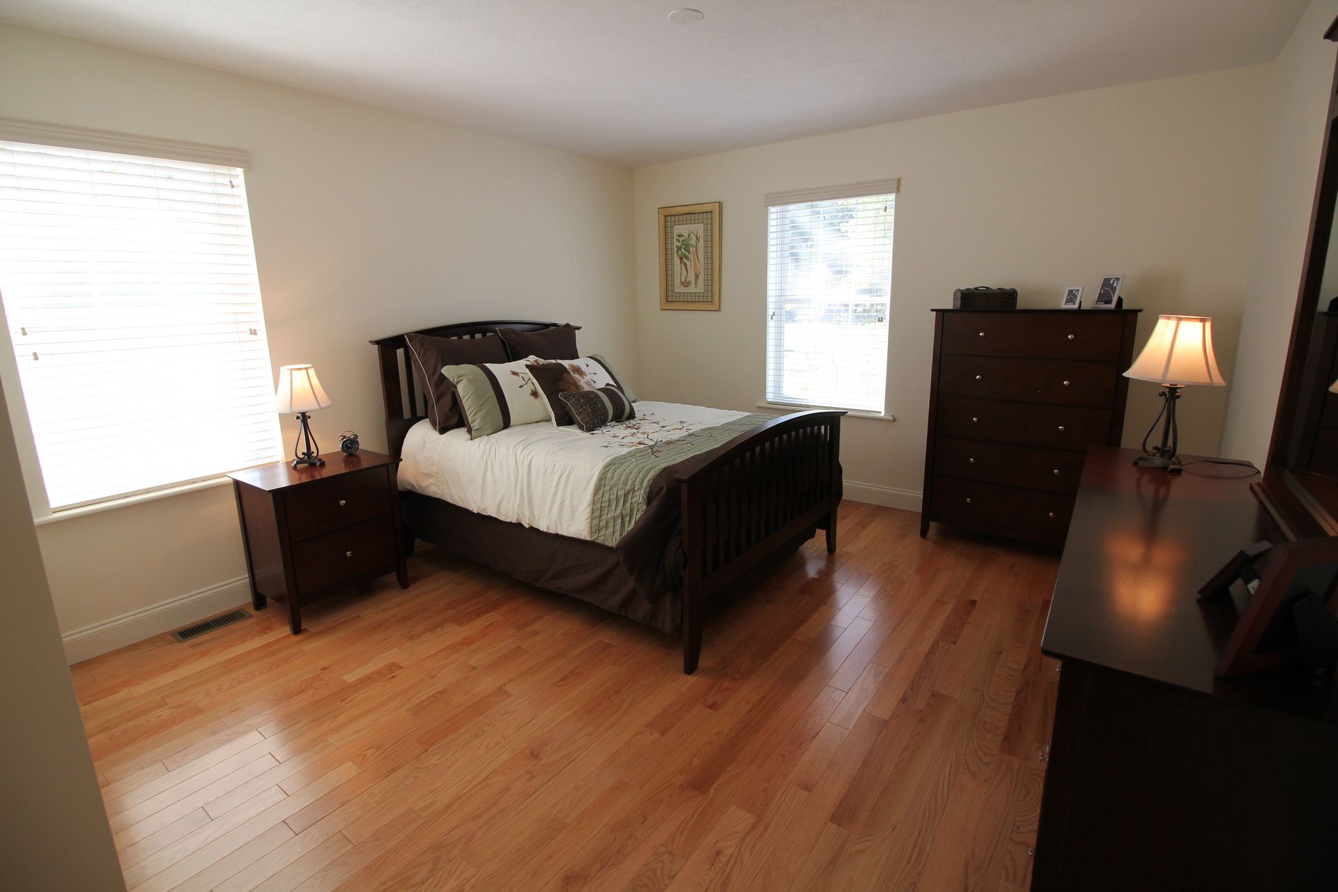A bedroom with hardwood floors and a large bed