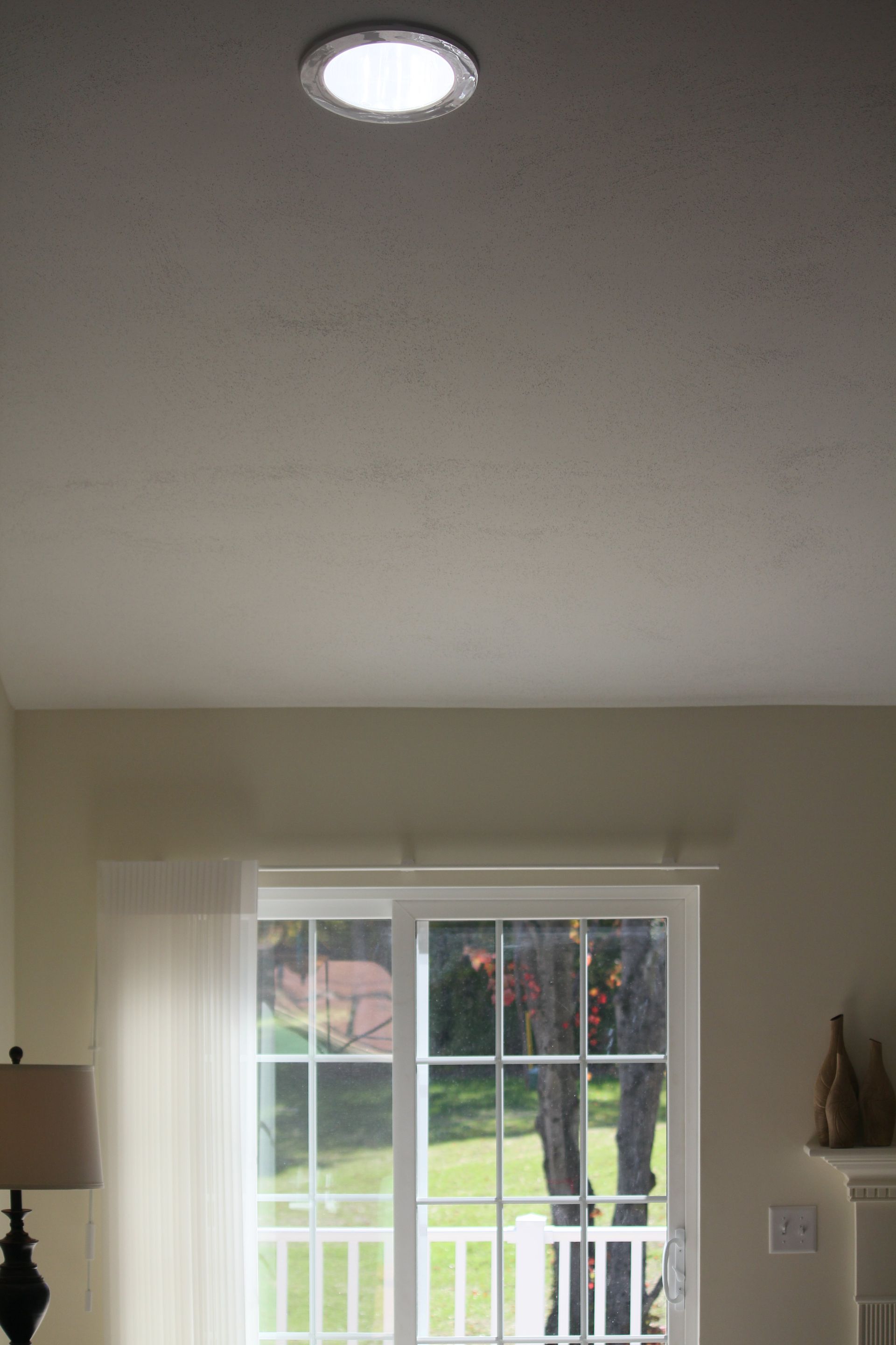 A living room with a sliding glass door and a ceiling light.