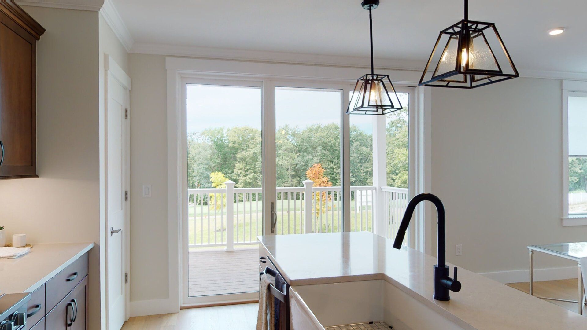A kitchen with a sink and a sliding glass door leading to a deck.
